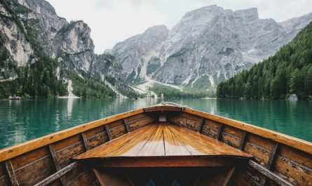 brown wooden boat moving towards the mountain