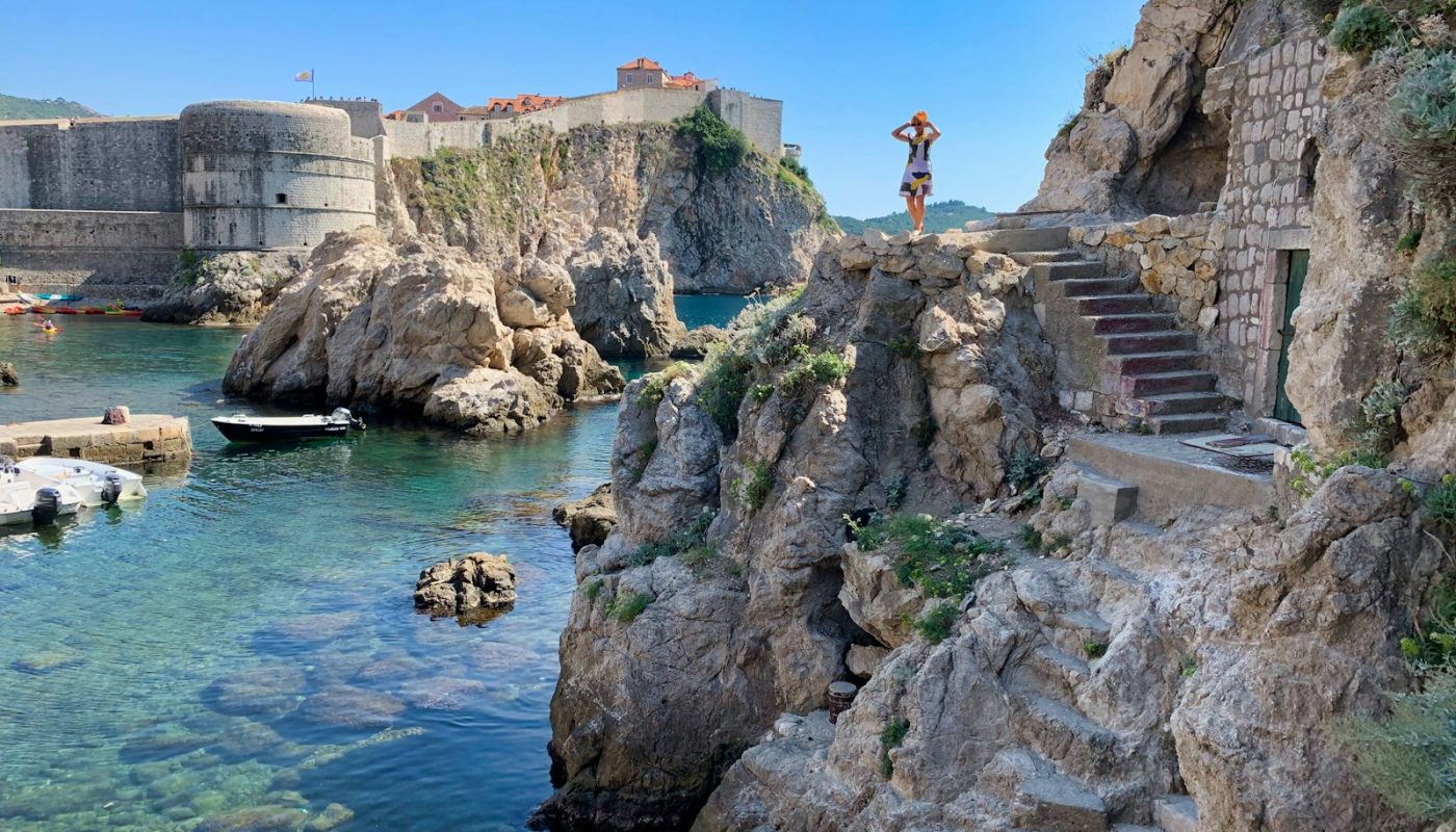man standing on rock formation near body of water during daytime