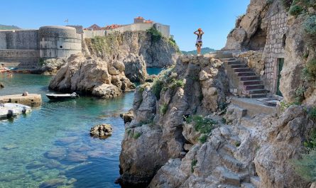 man standing on rock formation near body of water during daytime