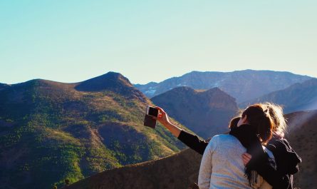 a woman taking a picture of the mountains with her cell phone