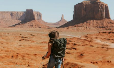 woman with black backpack standing on brown dessert