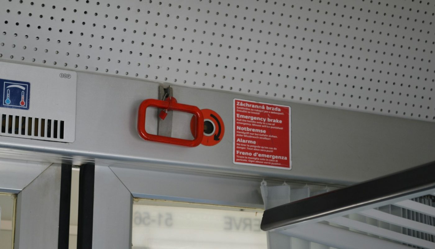 Red emergency handle and warning sign on a train.