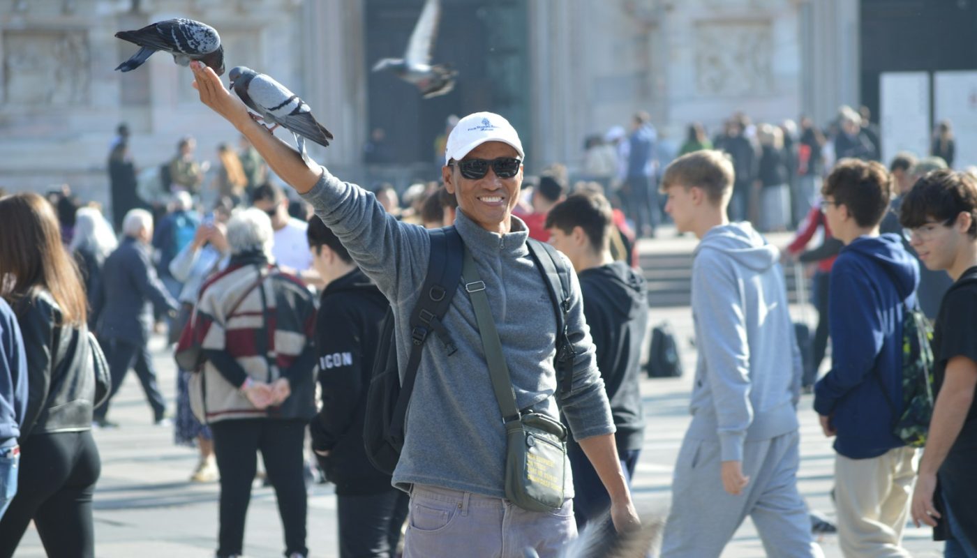 A man with a bird on his arm in the middle of a crowd of people