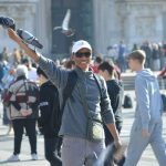 A man with a bird on his arm in the middle of a crowd of people